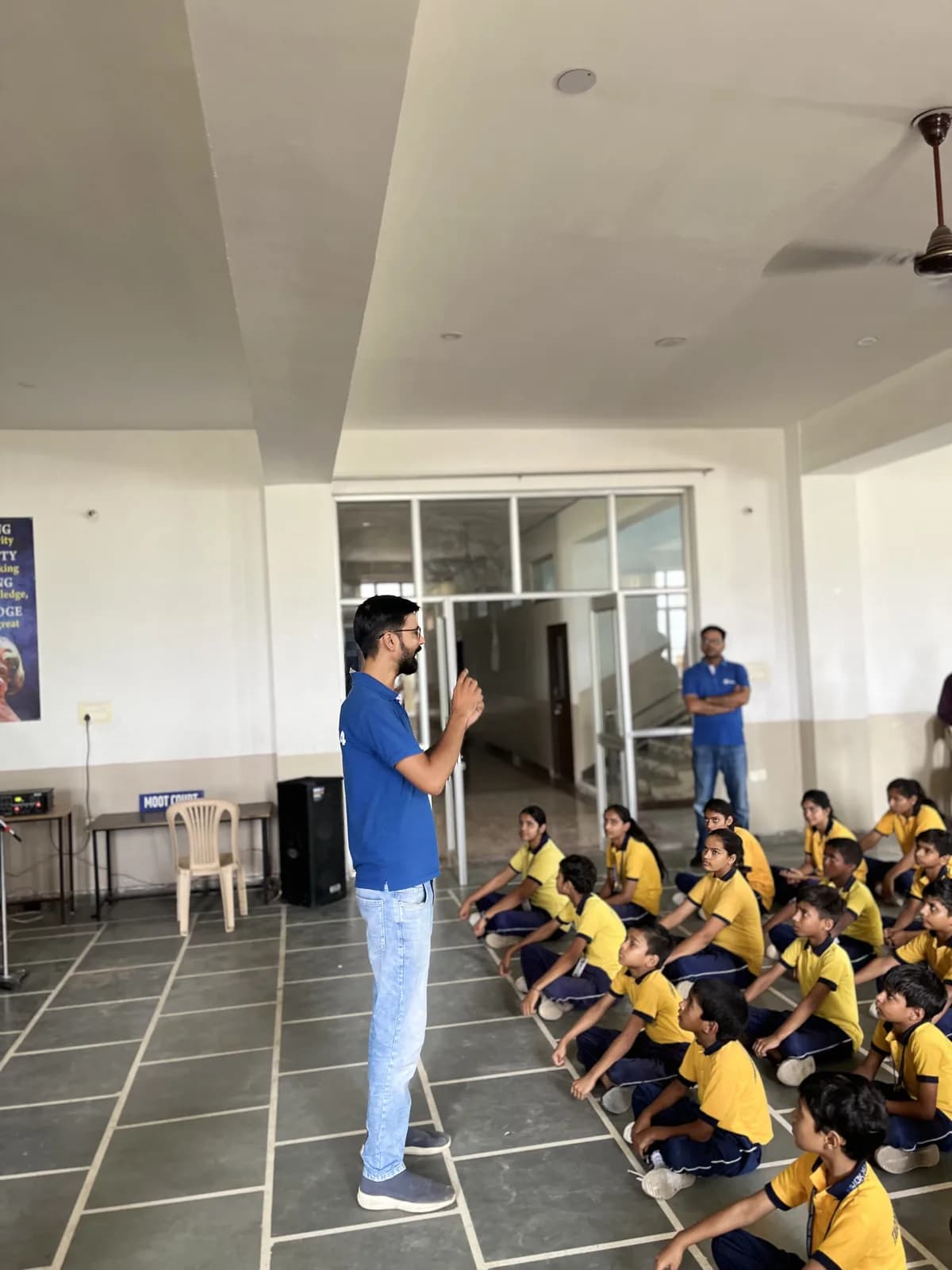 A teacher addressing students in the assembly hall