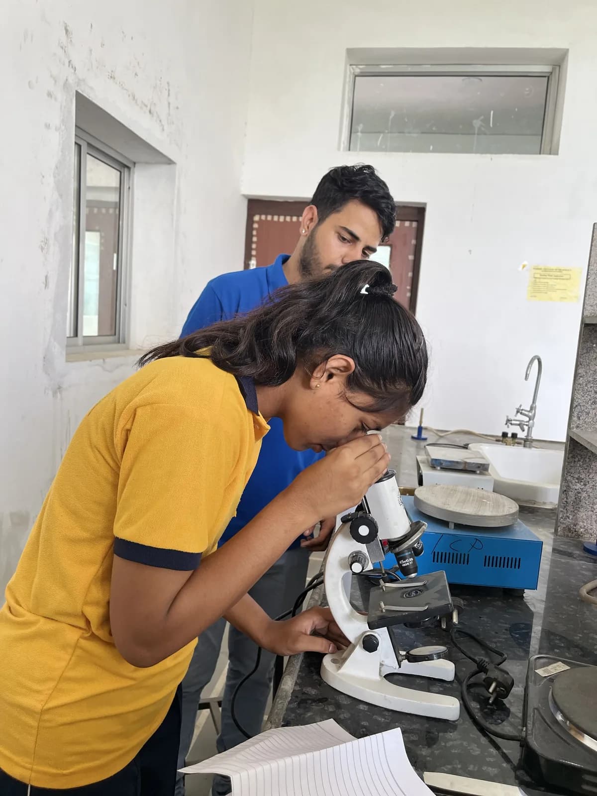 A pupil examining a slide under the microscope