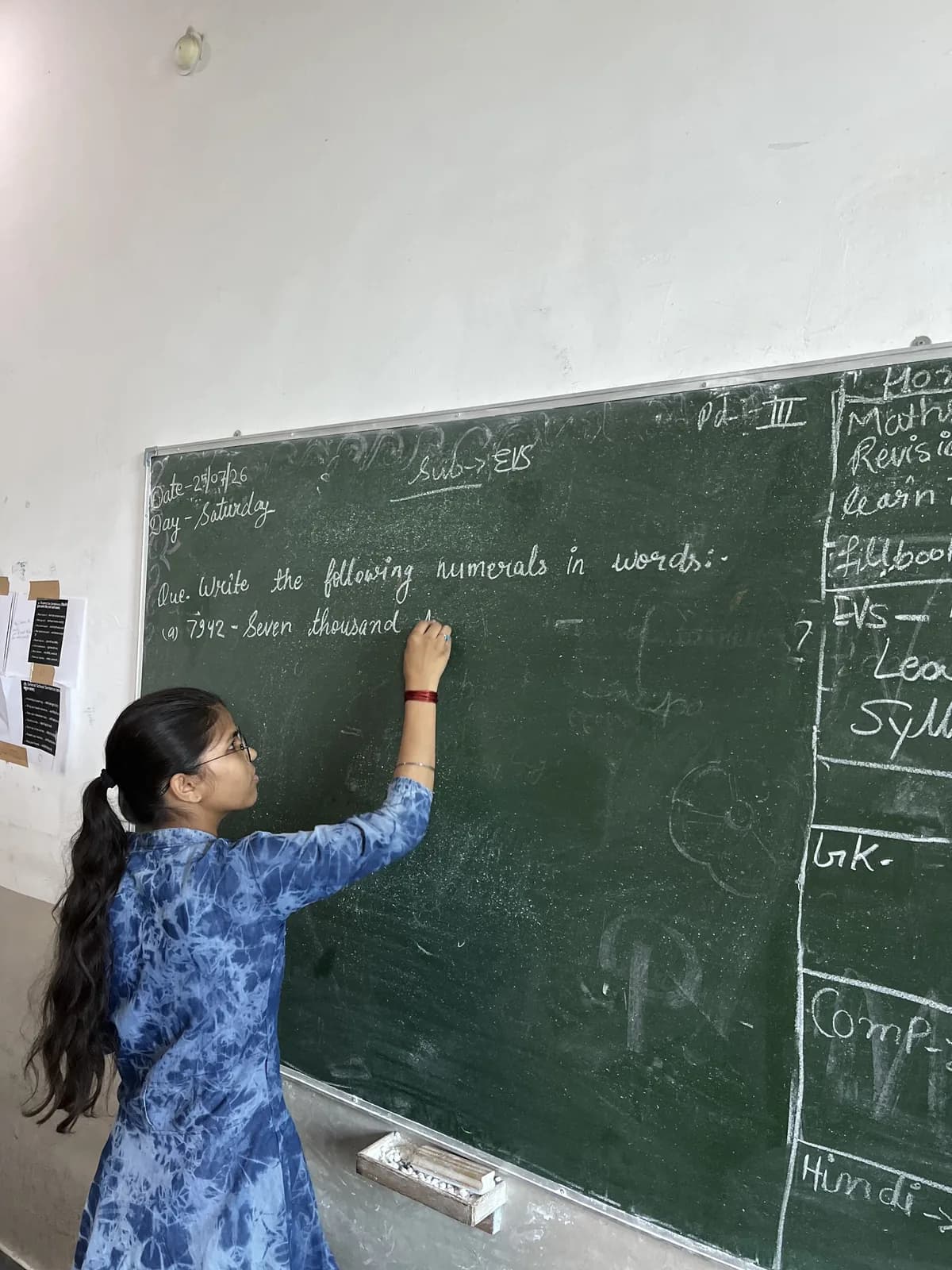 A teacher writing the day's lesson on the blackboard